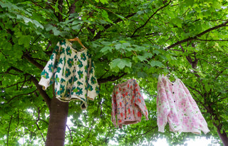 The Medibody Apparel green, pink and pastel pink flower cardigans hanging on green maple tree branches.